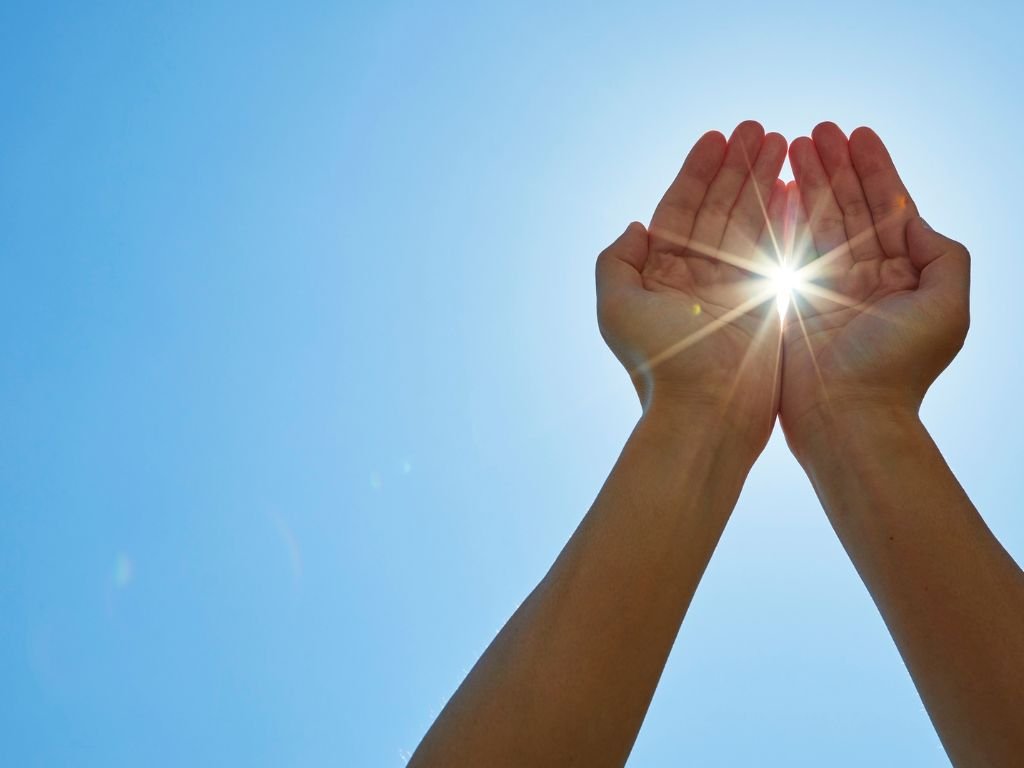 hands holding a bright llight with sky blue background